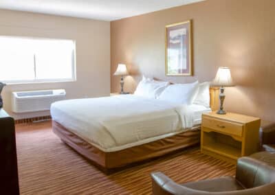 First Choice Inn's single bed Queen Room with bedside tables and a leather couch